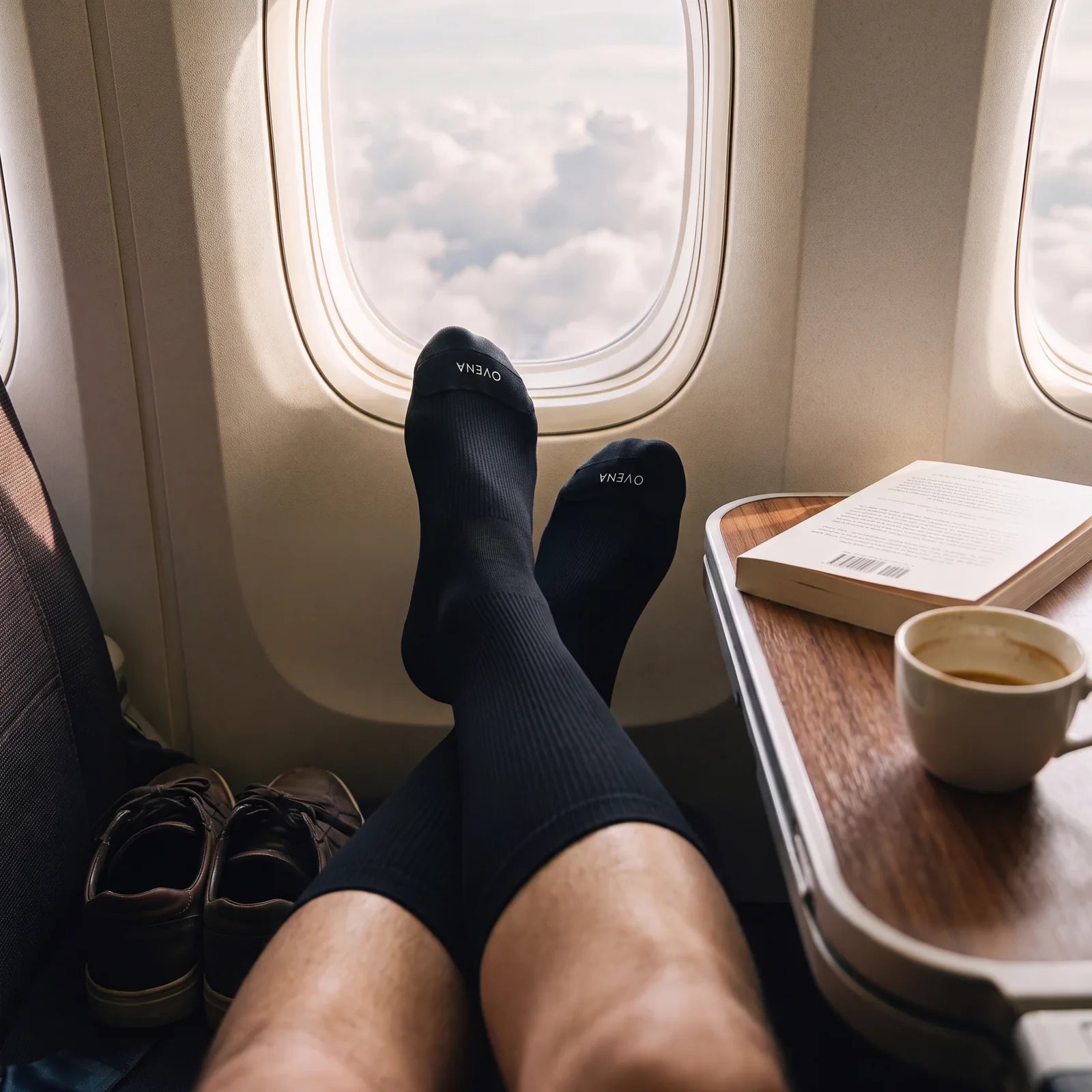 Traveler relaxing in an airplane window seat wearing black OVENA compression socks